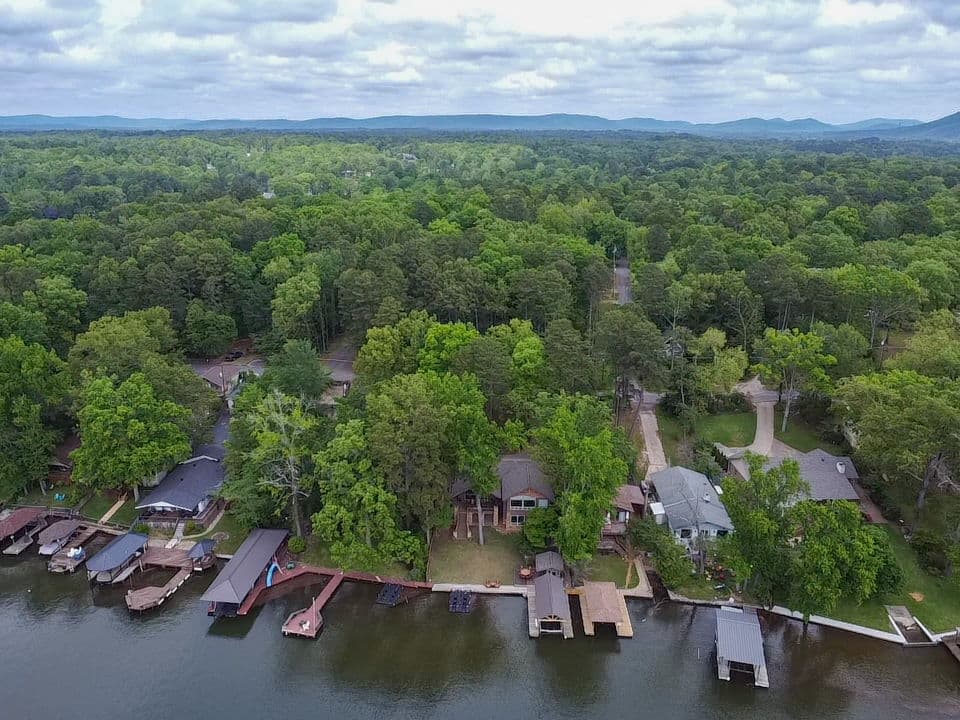 Aerial photo of a wooded lakefront lined with covered boat docks in Hot Springs, Arkansas, with the mountains on the horizon