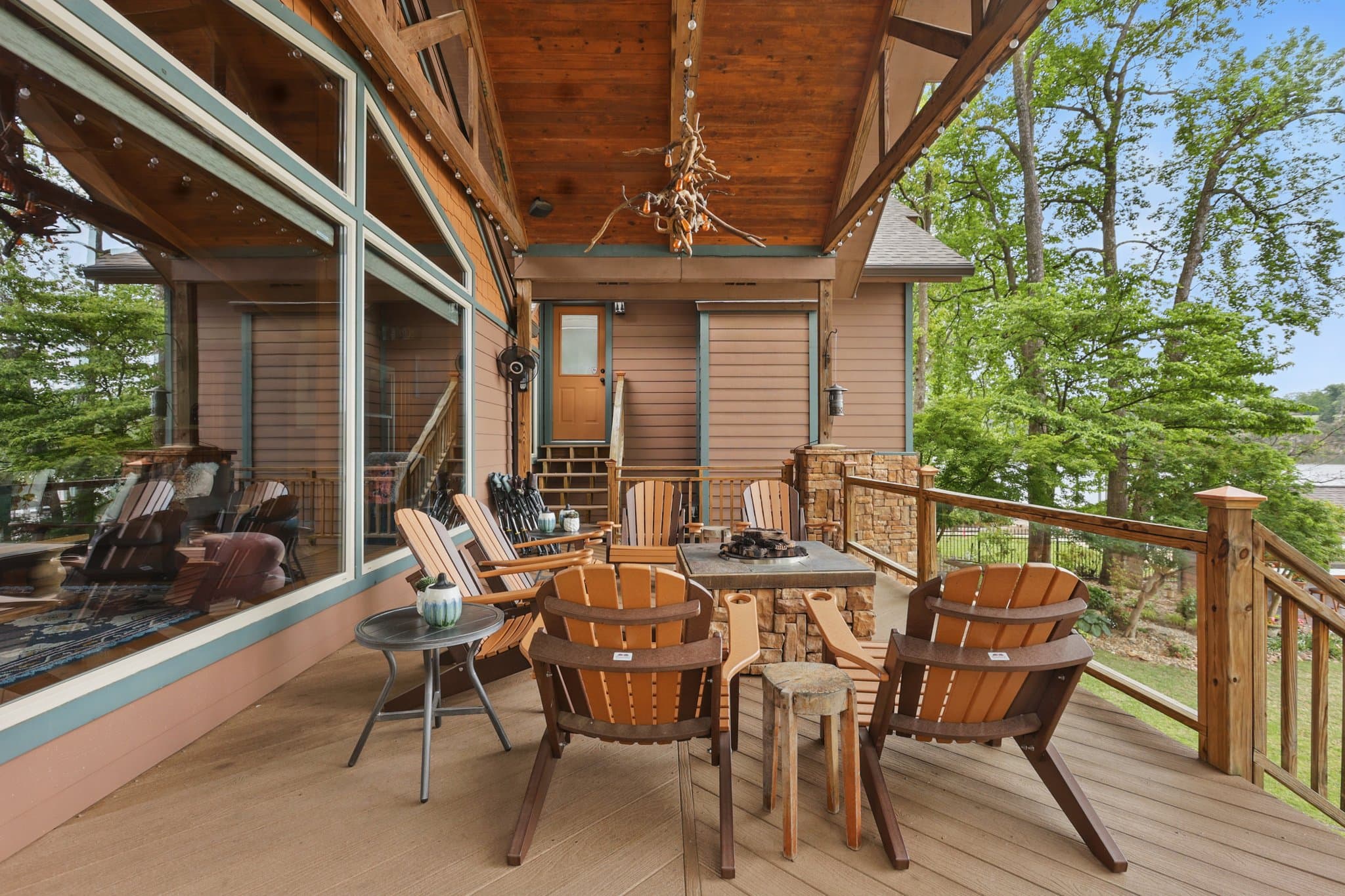 Covered deck with wood chairs and a table under a timber ceiling at a short term rental cabin in Hot Springs, Arkansas