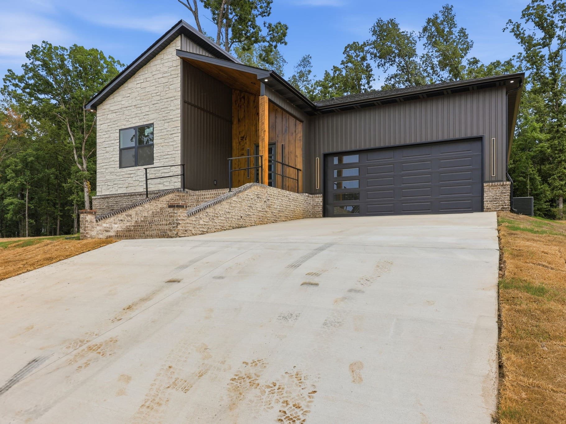 Front elevation of a new construction home in Cabot, Arkansas, photographed in bright daylight, with a wide concrete driveway running up to the garage