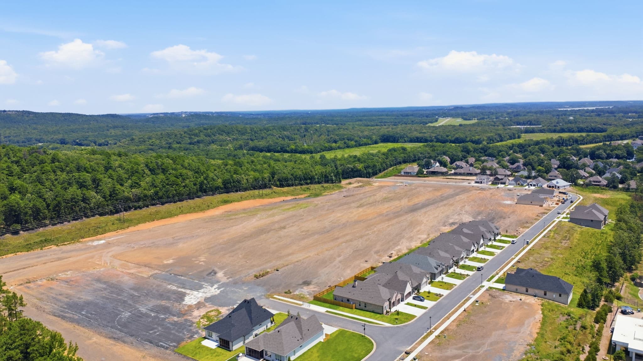 Drone photo of a new residential development in Little Rock, Arkansas, with graded lots beside a street of finished homes