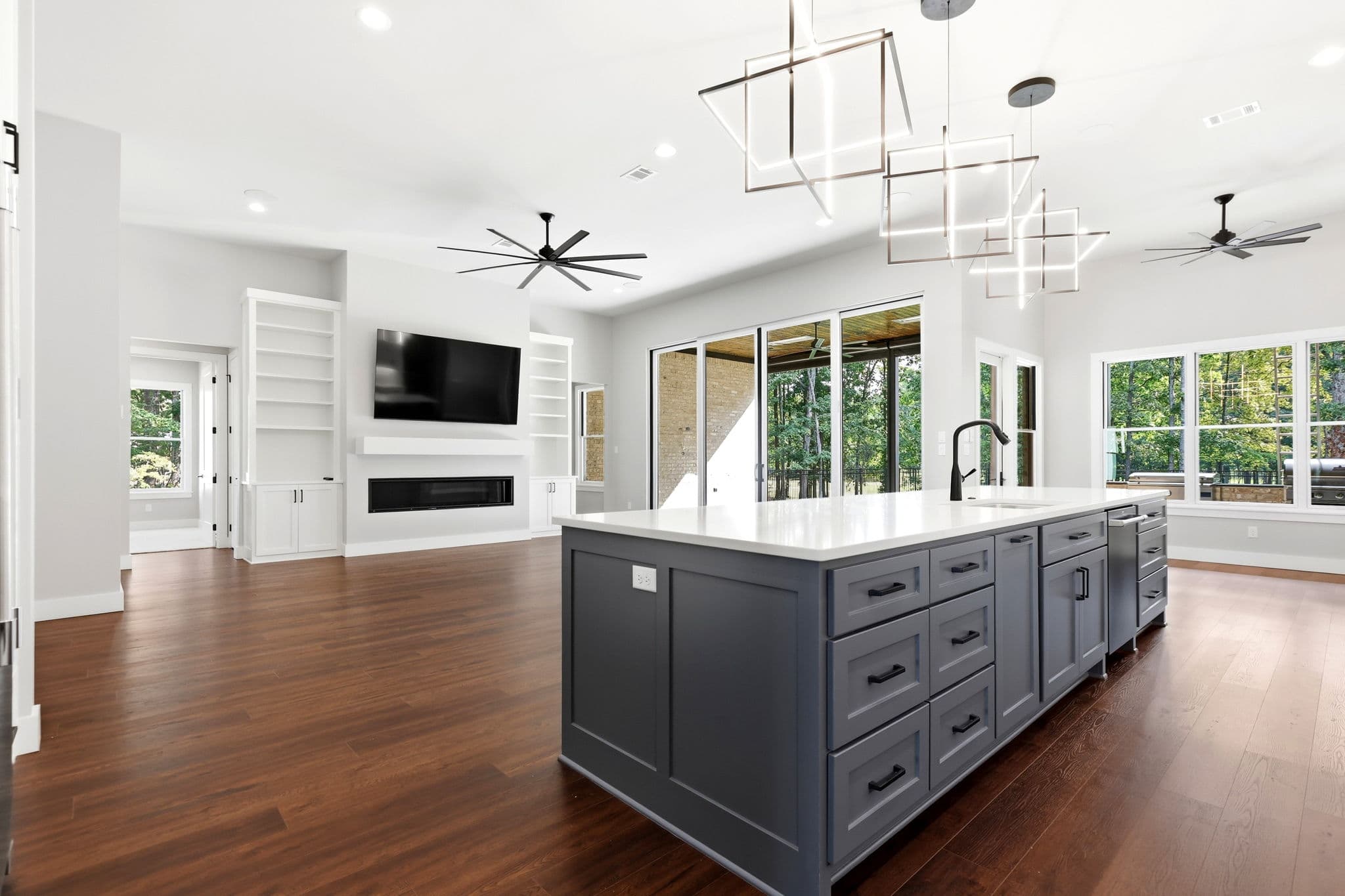 Kitchen island with shaker drawer fronts opening to a great room with a linear fireplace in a new construction home in Little Rock, Arkansas