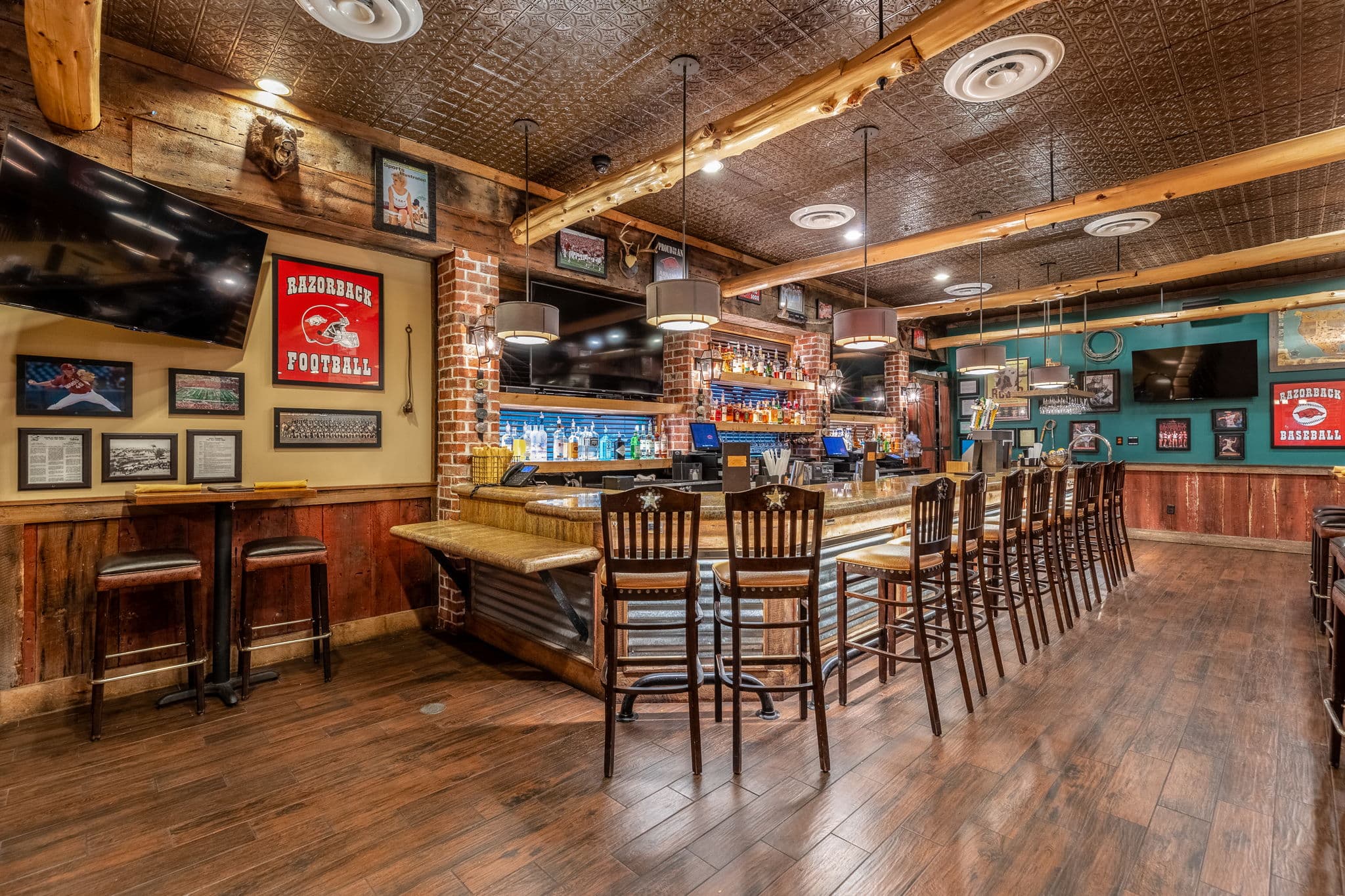 Bar with high stools, a pressed tin ceiling and framed memorabilia on exposed brick at 10 Anglers Way in Little Rock, Arkansas