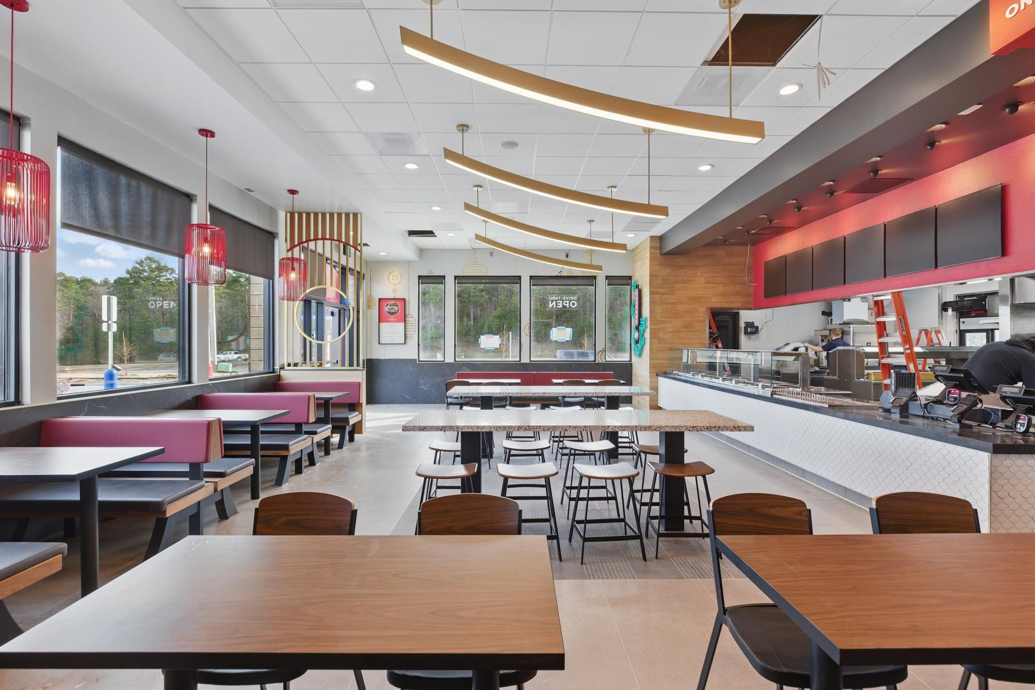 Dining room with gold pendant lighting and booths inside a quick service restaurant in Maumelle, Arkansas