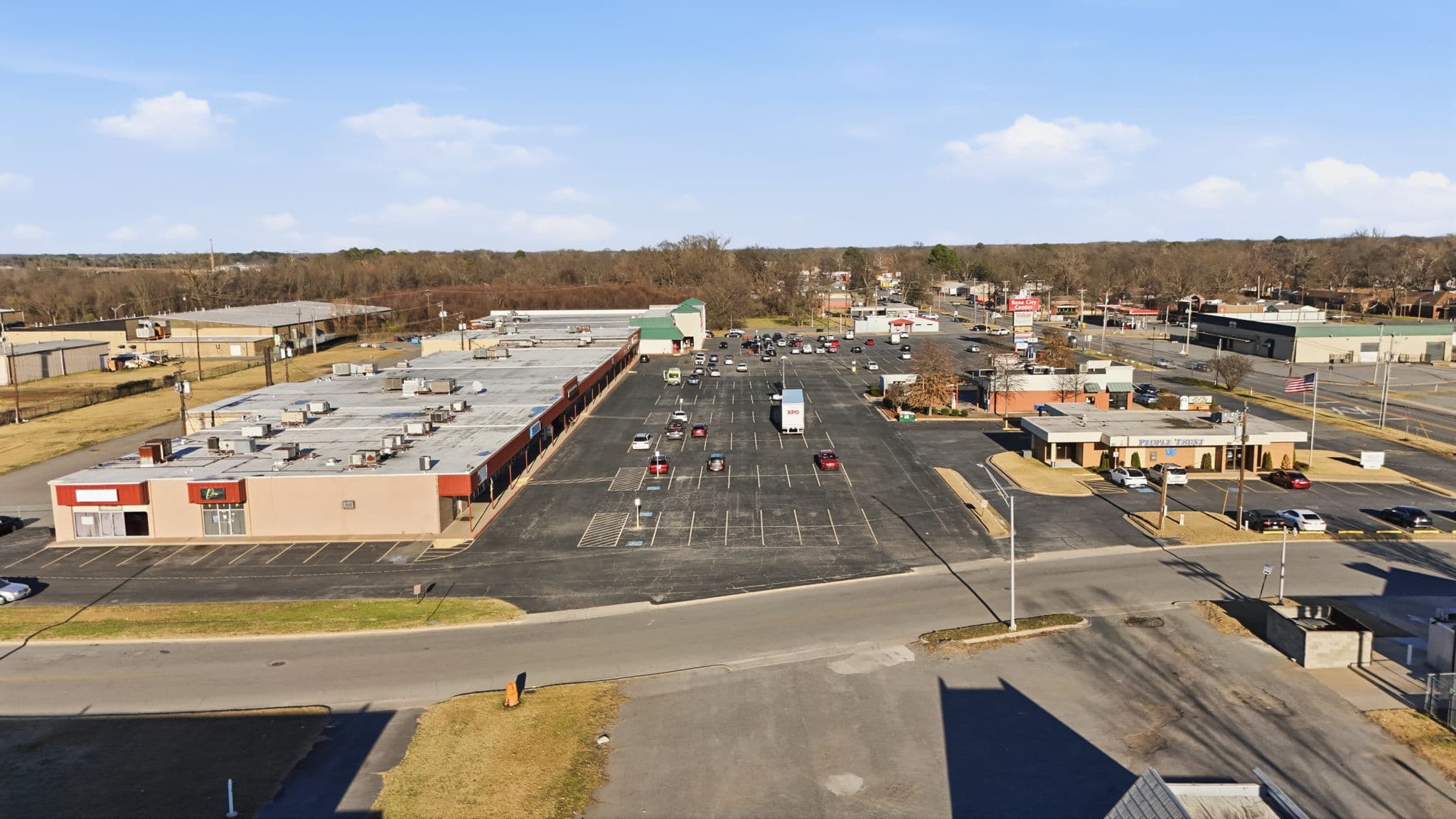 Low aerial of a row of retail storefronts and the parking lot at a shopping center on East Broadway in North Little Rock, Arkansas