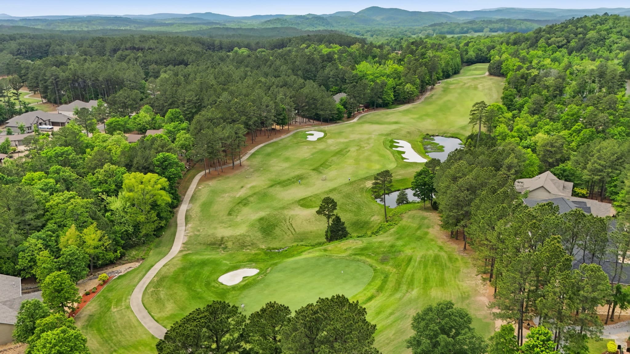 Aerial photo over the golf course in Hot Springs Village, Arkansas, with homes set along the fairway and wooded hills behind